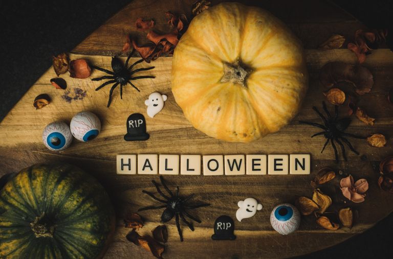 Widok z góry na stół na którym jest Napis Halloween, dynie, pająki, duszki, oczy i suszone dekoracje